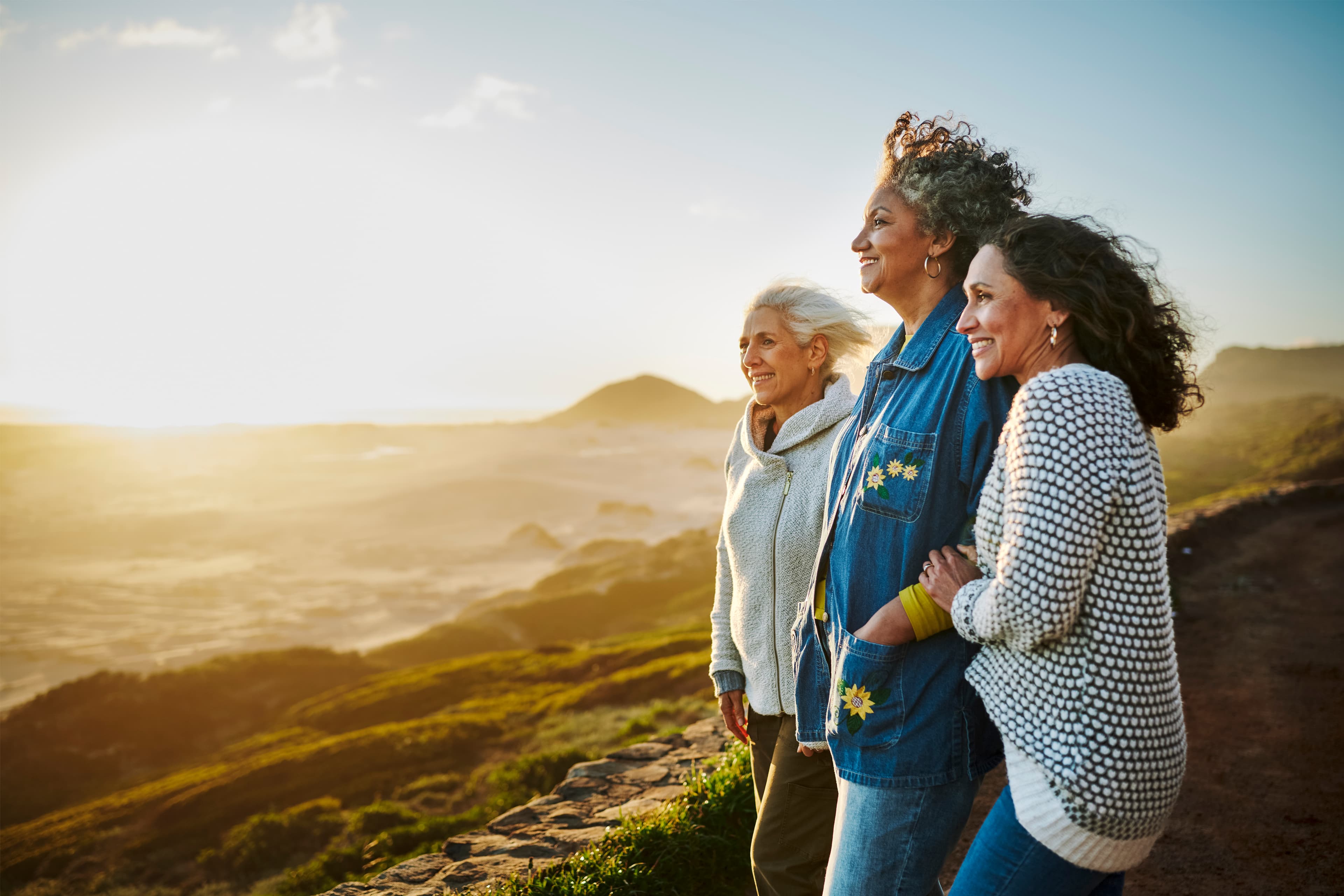 three older women standing on a hill and looking over the horizon